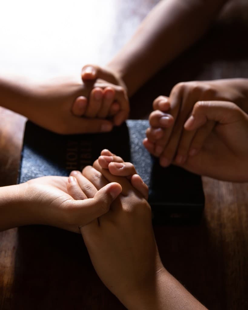 Hands clasped in prayer around a Bible